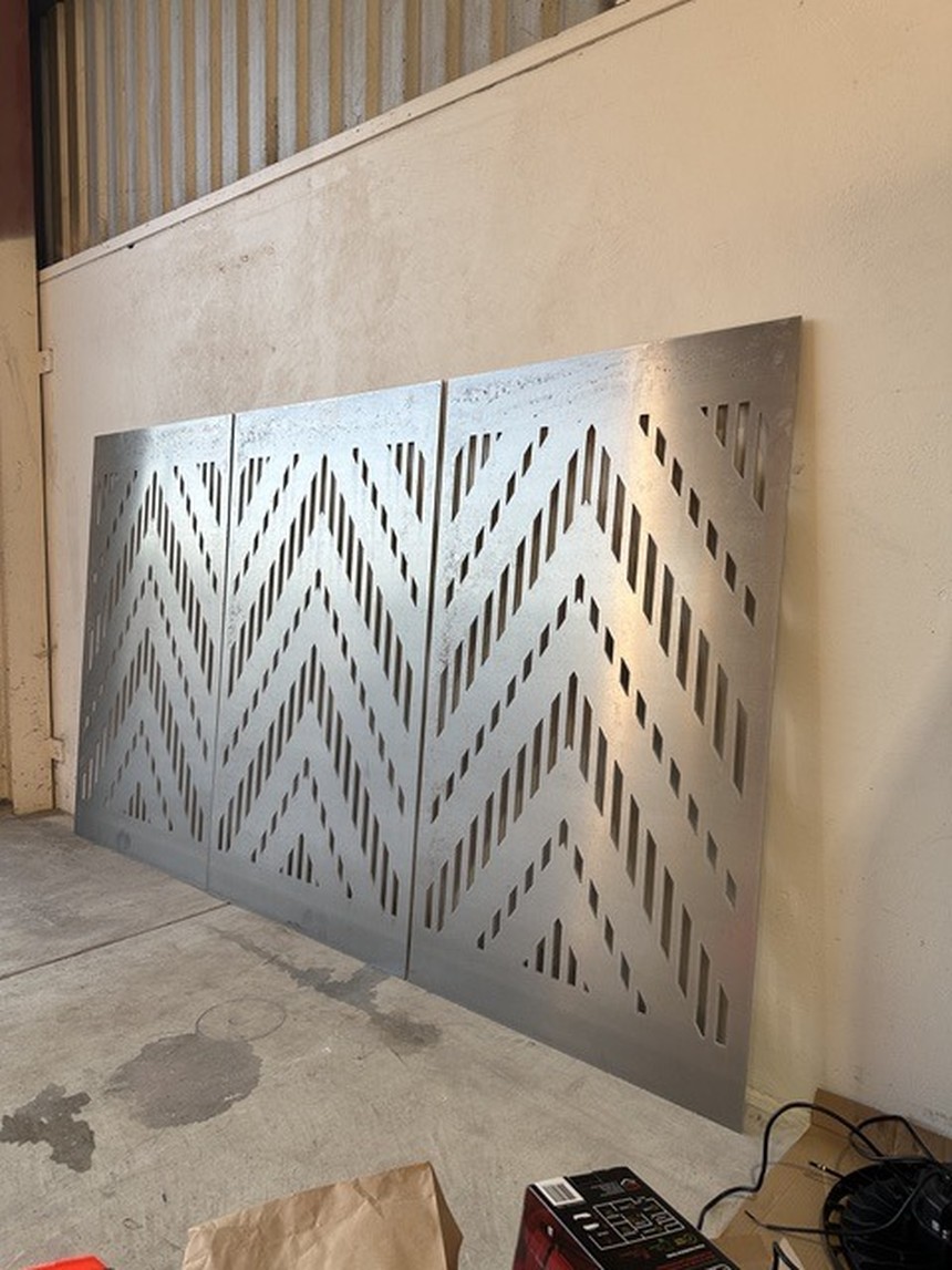 Panel study: chevron-perforated metal panels leaning against a wall in the workshop